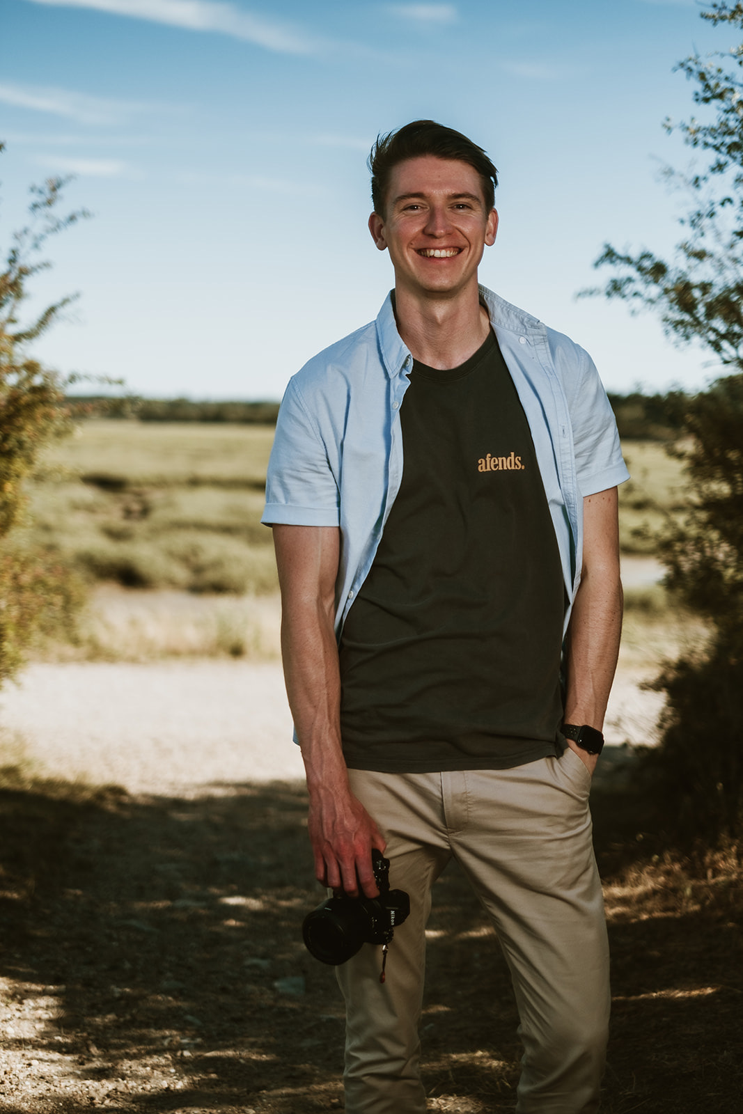 Andrew smiling with his camera in the countryside