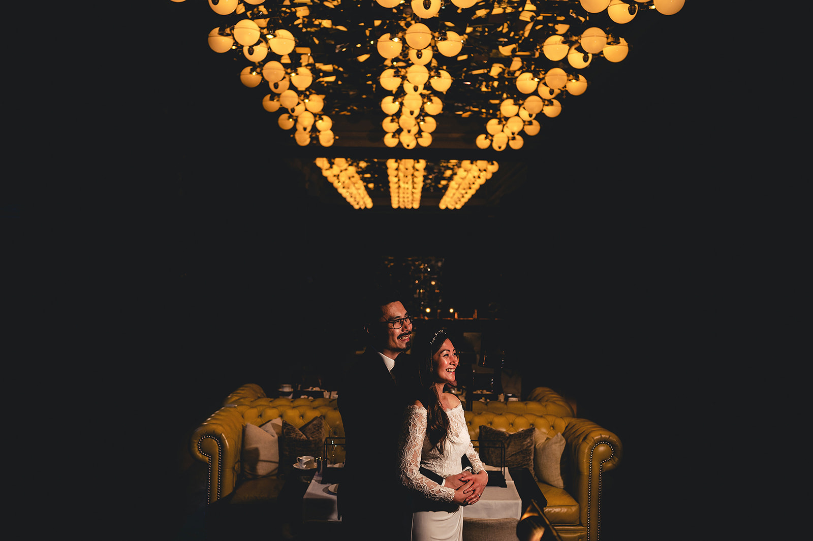 A newly married couple together beneath warm golden lights at the Rosewood Hotel