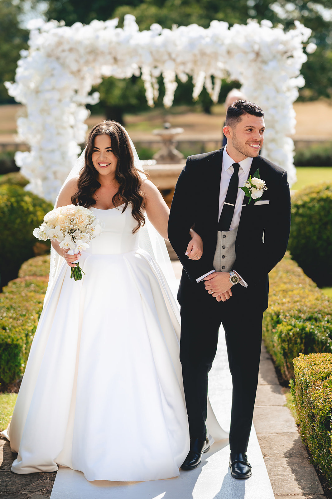 Meghan and Jason together beneath a white floral arch