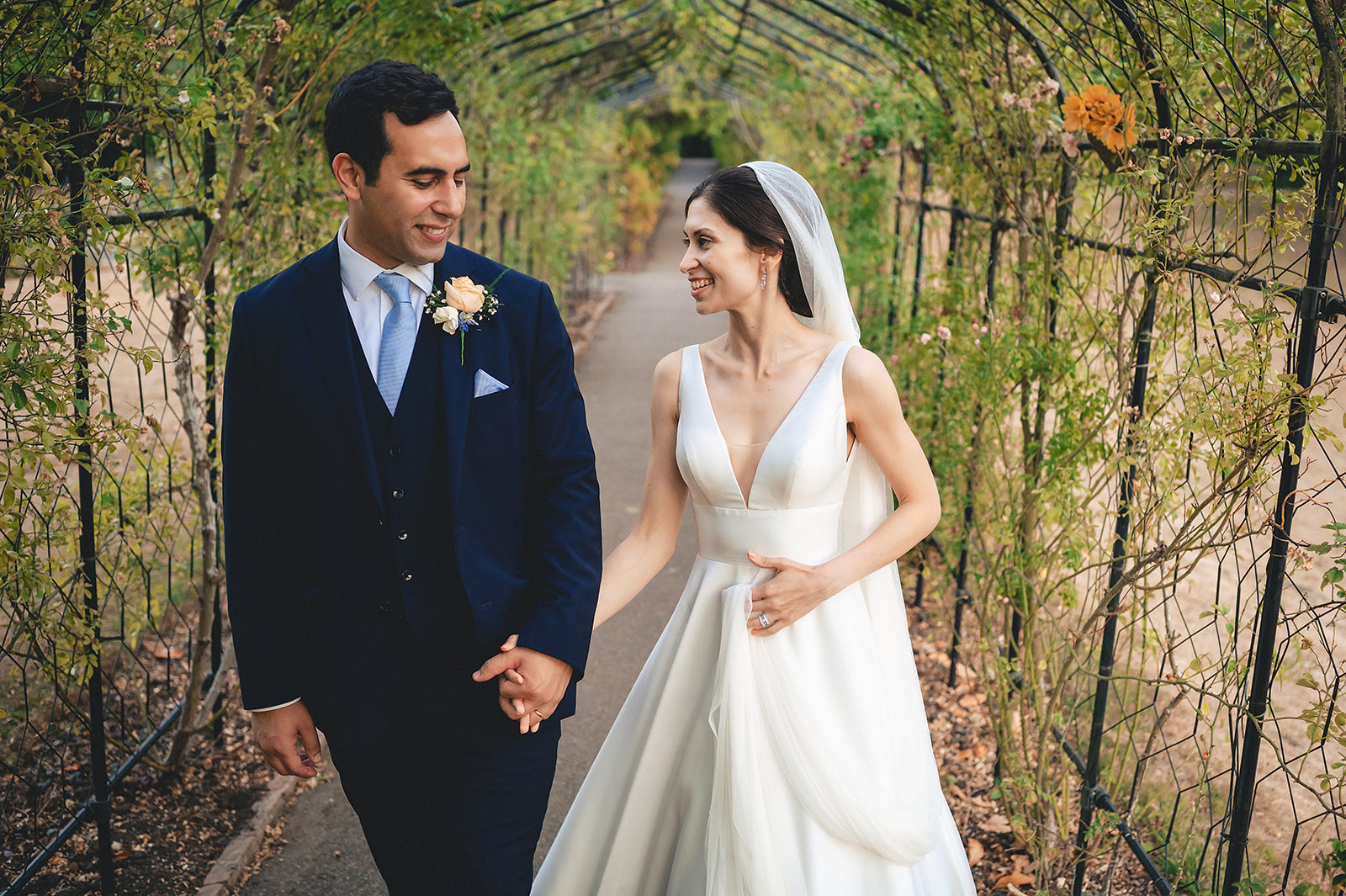 Emma and Raif holding hands beneath a stone arch at Nonsuch Mansion