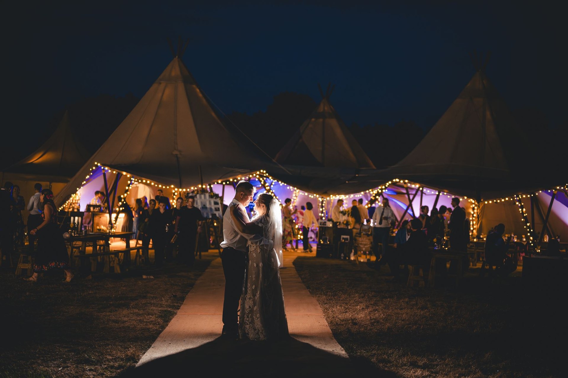 A couple beneath glowing lights outside at night